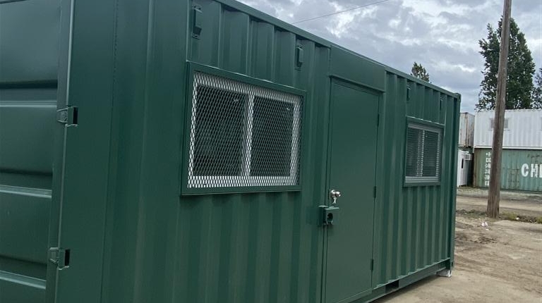 Photo shows custom modification of a 20' container with a "man door" and 2 windows, fully framed and reinforced with safety steel cage