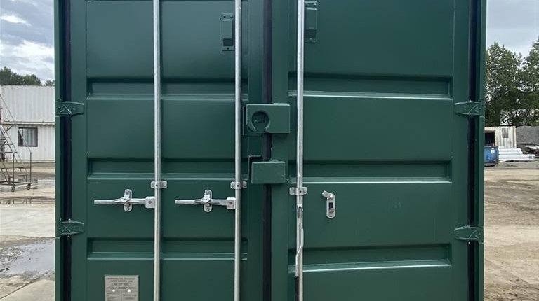 Photo showing a shipping container with barn doors facing the camera. Container has been freshly painted forest green, as per customer's specifications
